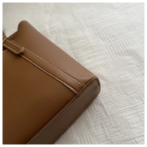 Détail du sac en similicuir marron foncé avec des coutures contrastées blanches
