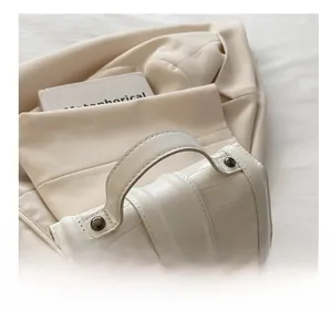 Detail of white crocodile embossed leather bag with wide handle and metal chain strap