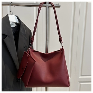 Detail of burgundy leather tote bag with unique knotted strap and matching pouch set