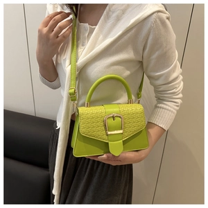 Détail du sac à main vert avec texture tressée et fermoir en métal doré sur le rabat