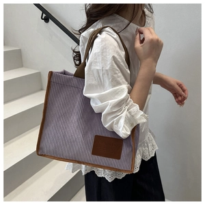 Detail of purple corduroy tote bag with brown straps and embossed fashion leather patch