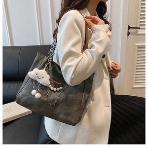 Detail of dark grey tote bag with metal chain, pearl strap and plush cloud charm accent