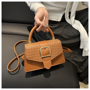 Gros plan sur le tissage marron et le cuir lisse d'un sac bandoulière rétro chic