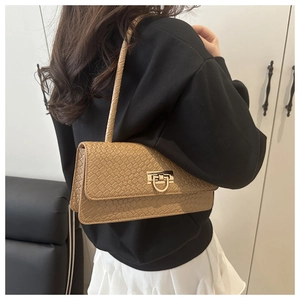 Detail of light brown baguette bag with faux crocodile texture and gold horseshoe buckle