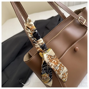 Détail d'un sac cabas en PU marron avec un foulard en soie et des surpiqûres blanches contrastées
