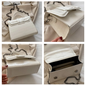 Detail view of white crocodile pattern handbag with metal chain strap and spacious interior