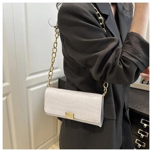 Détail de la texture crocodile blanche et chaîne dorée sur ce sac à main à rabat chic
