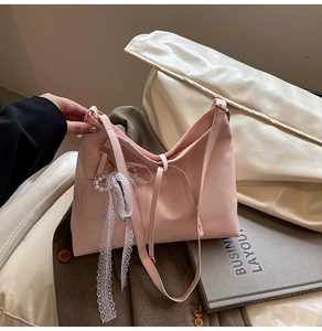 Detailed view of pink tote bag featuring a white lace bow and heart pearl pendant charm