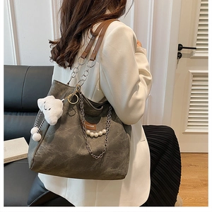 Detail of minimalist tote bag featuring pearl chain and plush cloud charm accessory