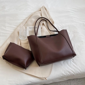 Dark brown matte leather tote bag and pouch set on a minimalist cream blazer background