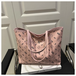 Detail of pink lychee leather tote bag featuring cartoon bear prints and metal rivet reinforcement