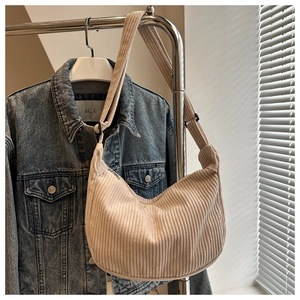 Close-up of beige corduroy crossbody bag with vertical texture and wide shoulder strap