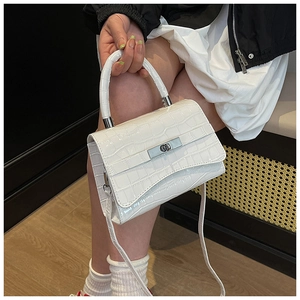 Close-up of white crocodile pattern shoulder bag with silver metal buckle on a model