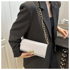 Détail du sac à main violet clair motif crocodile avec chaîne dorée et boucle métal