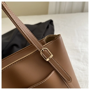 Gros plan détaillé d'un sac cabas en cuir PU marron avec surpiqûres et boucle dorée