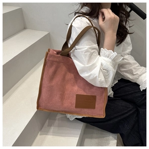 Detail of pink corduroy tote bag with brown leather patch and woven handles