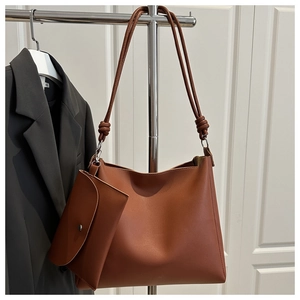Detail of caramel faux leather tote bag set with decorative knot straps and small pouch