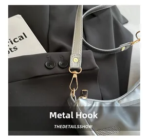 Detailansicht der goldene Metallhaken und silbergrauen Lederriemen der Tasche