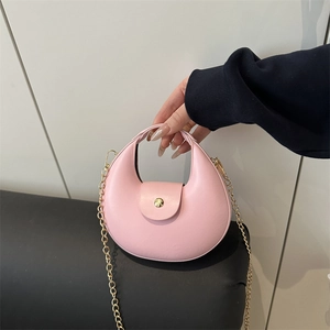 Pink crescent hobo bag with gold chain strap shown in a minimalist interior setting