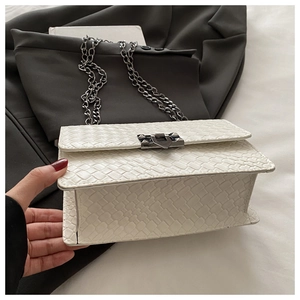 Close-up of white woven crossbody bag with silver chain strap and square metal lock