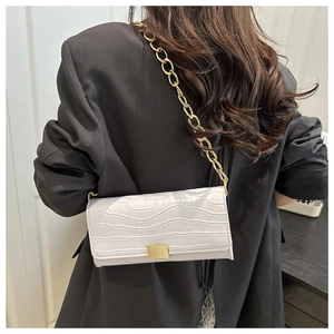 Détail d'un sac à bandoulière blanc motif crocodile avec chaîne dorée et fermoir métal
