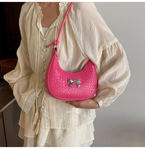 Detail of woven fuchsia hobo bag with a silver metallic bow on a white dress