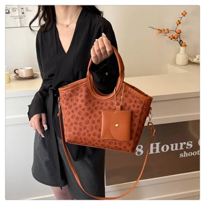 Detail of vintage brown tote bag with floral patterns, charm, and removable strap