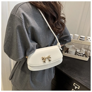 Detail of white PU leather crossbody bag featuring a golden bow buckle and knotted strap
