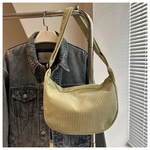 Detailed close-up of light green corduroy hobo bag with adjustable strap and textured fabric