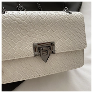 Close-up of beige woven leather bag texture and gunmetal rotary metal lock detail