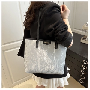 Detail of silver metallic crinkled tote bag with fashion label and black shoulder straps