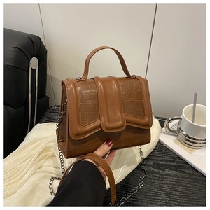 Détail du sac bandoulière vintage marron avec texture crocodile et chaîne en métal