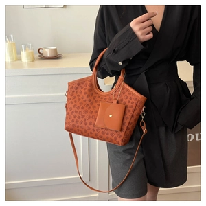 Detail of orange-brown printed tote bag with hanging envelope wallet and gold chain