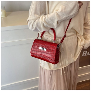 Model showing a red faux crocodile leather handbag with silver lock and shoulder strap