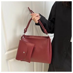 Detail of burgundy leather tote bag with knotted shoulder strap and matching mini pouch