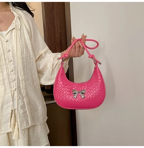 Detail of pink woven crescent bag featuring a silver metal bow and knot handle strap
