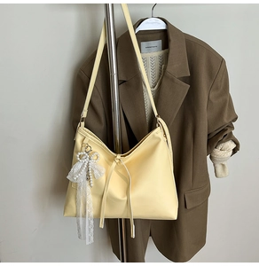Detail of light yellow tote bag with ribbon bow and elegant lace pearl charm accessory