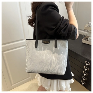 Detail of silver metallic tote bag with wrinkled texture and black thin shoulder straps