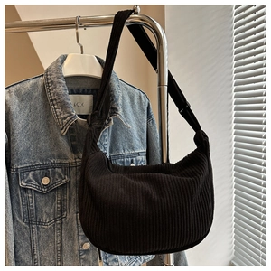 Detail of black corduroy crescent bag with adjustable strap hanging on a hanger