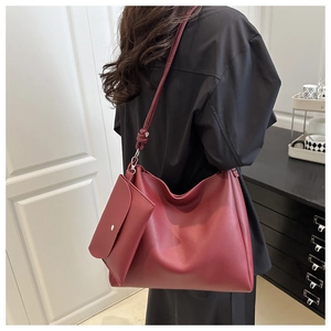 Deep burgundy leather hobo tote bag with matching pouch shown on a model for scale