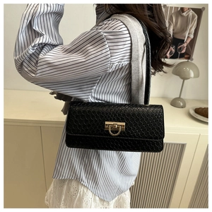 Detail of black woven texture shoulder bag with gold U-shaped metal buckle on model