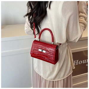 Detail of red crocodile texture handbag with glossy finish and metallic gold clasp