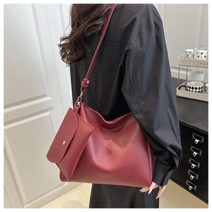 Detail of burgundy bucket bag with inner pouch and decorative shoulder strap knot