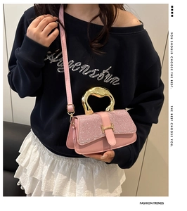 Close-up of pink glitter crossbody bag with geometric gold handle and H-shaped clasp