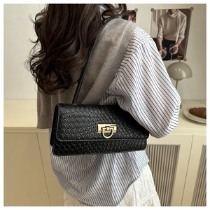 Detail of black woven shoulder bag with gold hardware and chic French retro styling