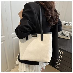 Close-up of white pleated tote bag with black trim and golden FASHION logo detail