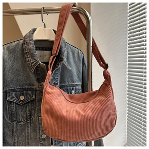 Detailed texture of the corduroy crossbody bag in a vibrant pink-orange hue
