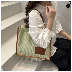 Close-up of light green corduroy tote bag with brown contrast trim and leather patch