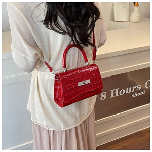 Detail of red crocodile texture handbag featuring silver lock and adjustable strap