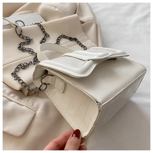 Détail du sac à main blanc texture crocodile avec grande boucle et chaîne en métal